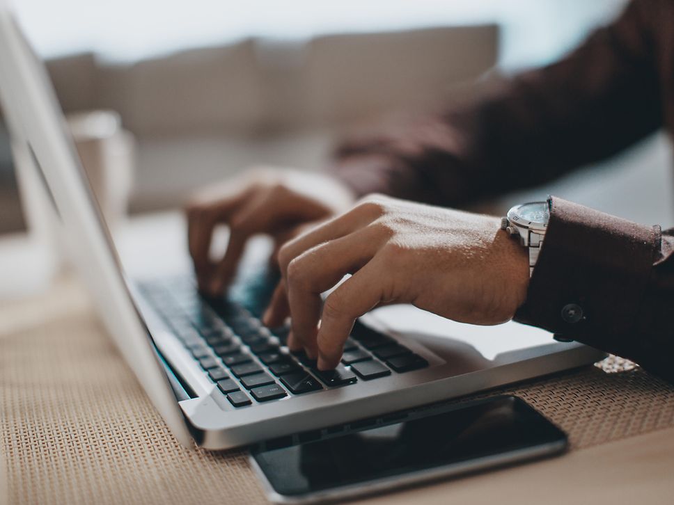 Ein Mann tipp etwas auf einer Laptop-Tastatur