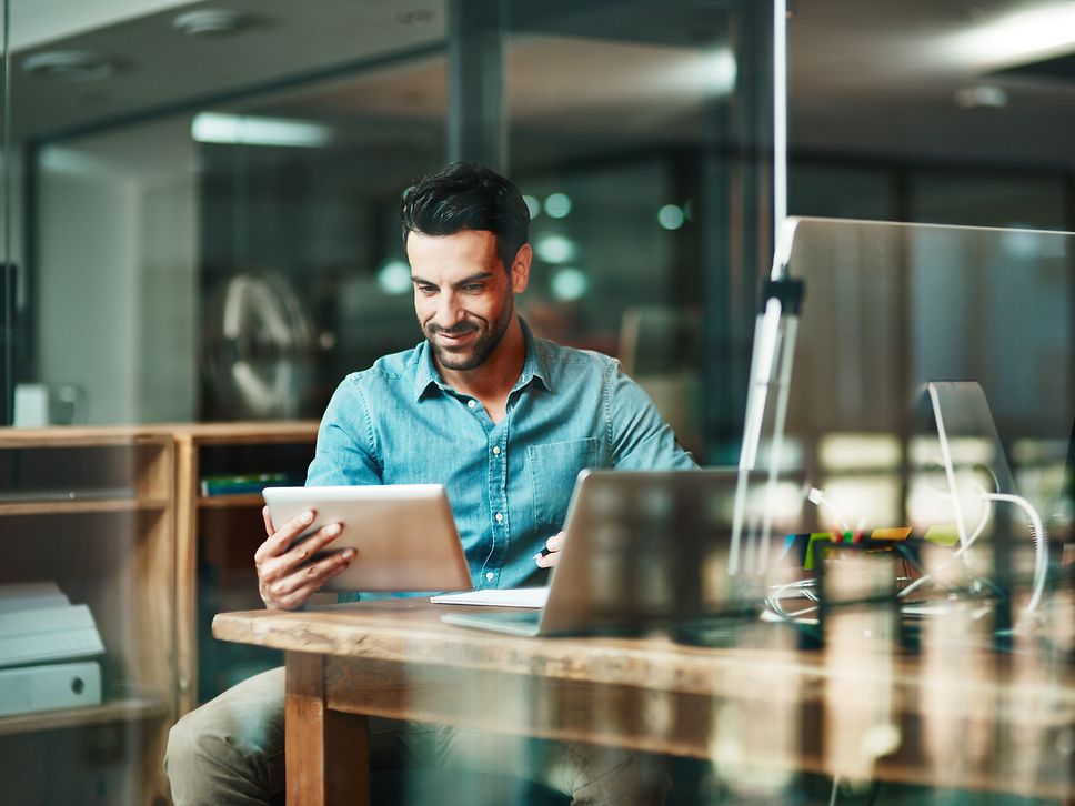 a man at a desk watching something on his tablet